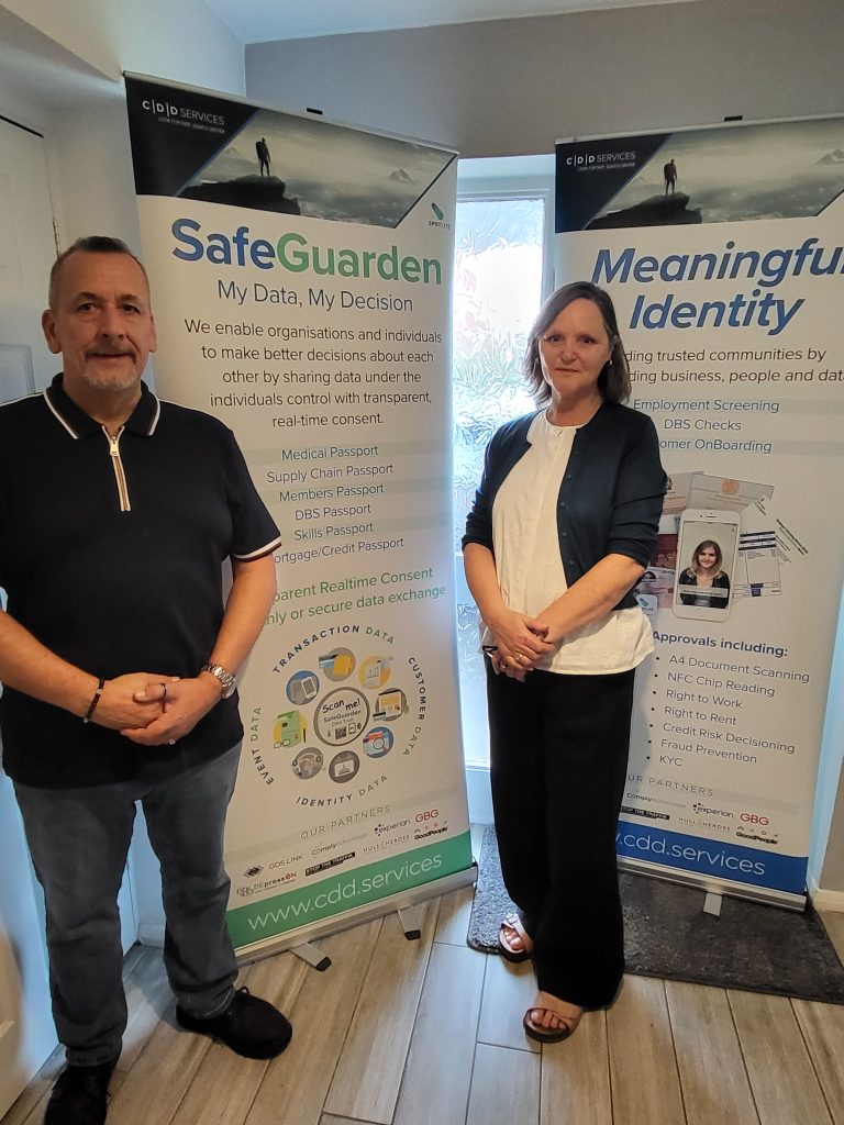 Two members of the Verve team standing in front of CDD Services pull-up banners for SafeGuarden and Meaningful Identity