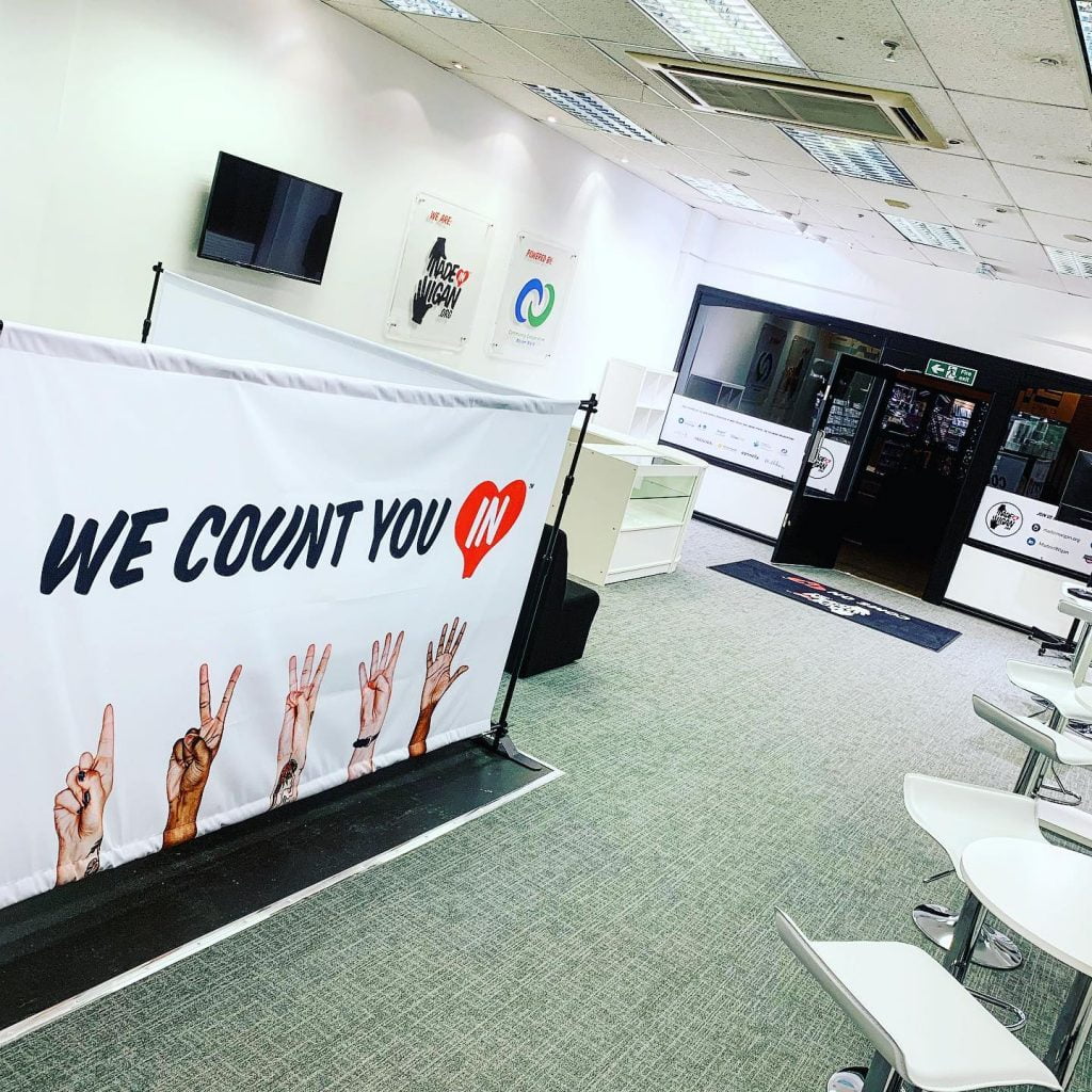 A 'We Count You In' banner showing five hands counting from one to five, set up in the Made in Wigan community space