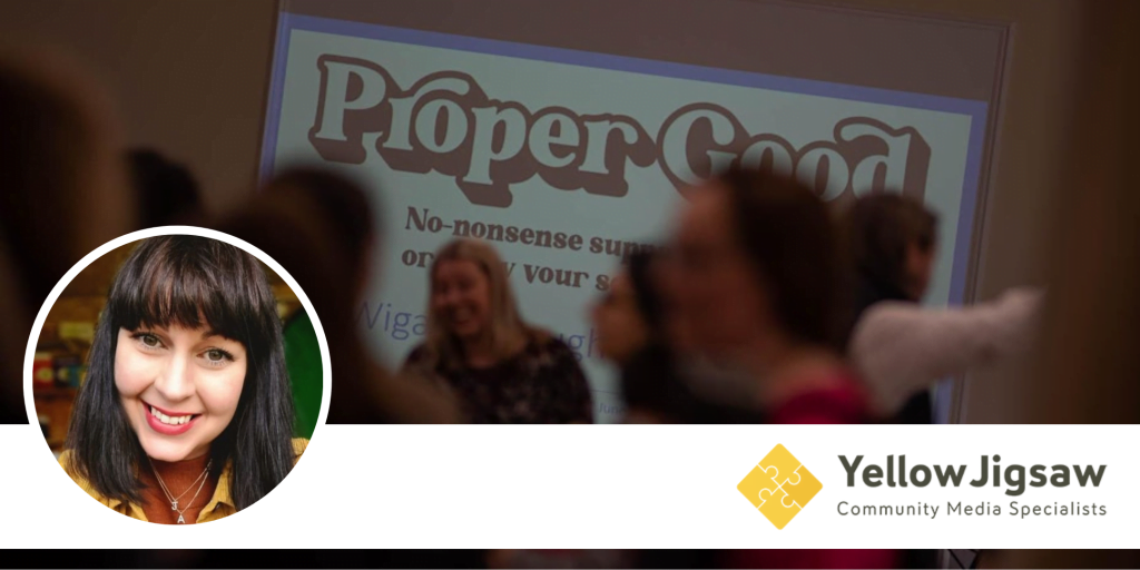 A Yellow Jigsaw banner with a speaker's portrait, photographed in front of a Proper Good poster